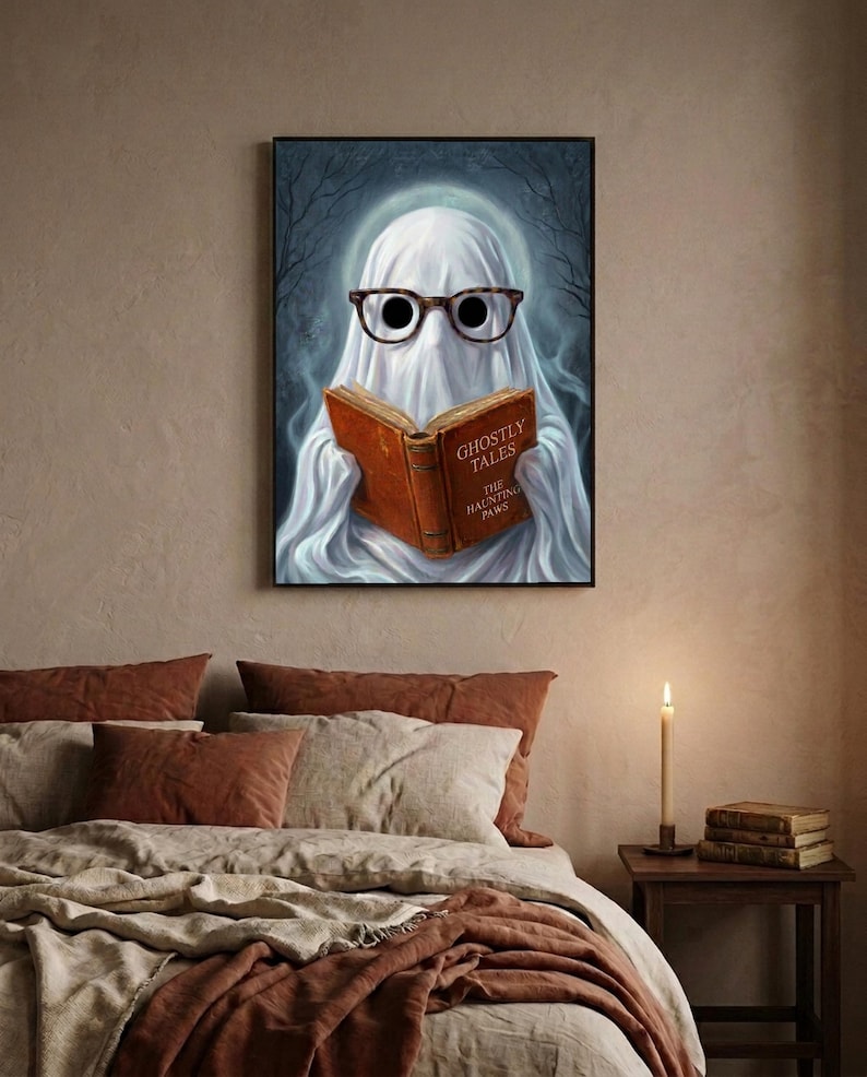 The ghost reading print framed above a bed with linen bedding and a lit candle on the nightstand