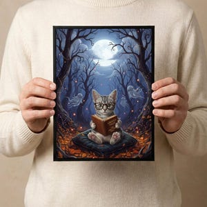 The kitten and ghosts ghost reading print held in both hands by a person in a cream sweater, showing its scale