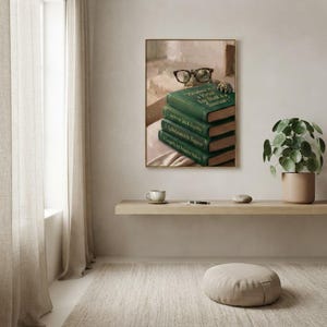 Turtle in round glasses peeking over books print framed above a restrained workspace with pale walls and a natural linen chair
