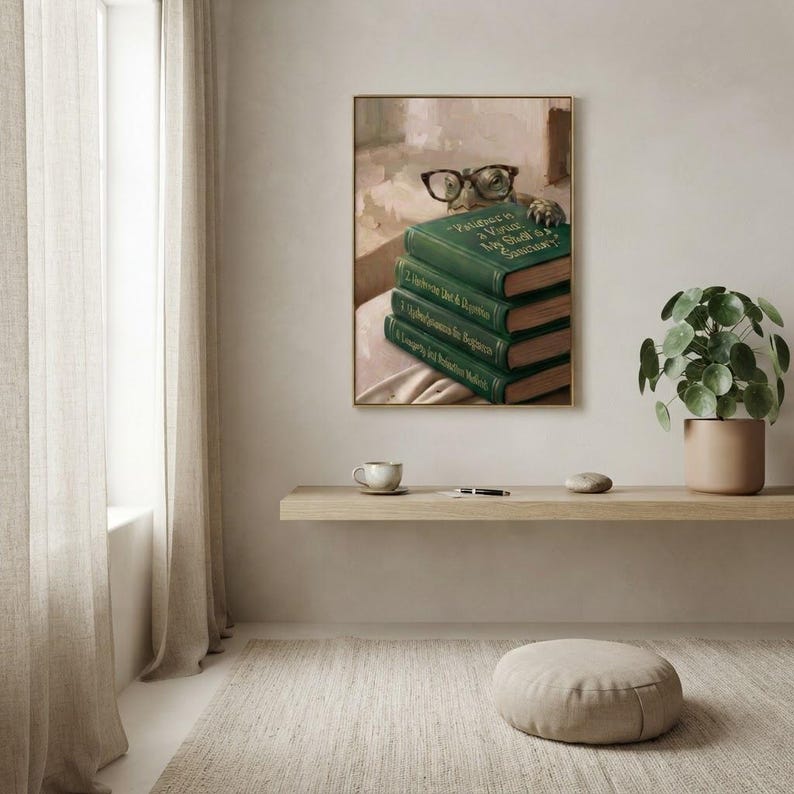 Turtle in round glasses peeking over books print framed above a restrained workspace with pale walls and a natural linen chair