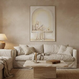 Wide living room view showing the woman reading nook wall art centered above a low sofa, gold frame, no mat.