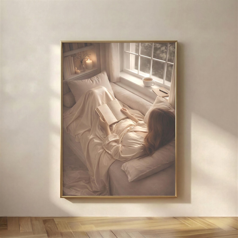 Beige minimalist wall art in a slim gold frame on a plain wall: aerial reading nook print of a woman reading in a window seat, soft beige and cream tones, digital download wall art.