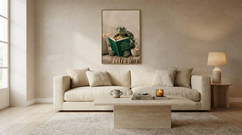 Wide view of a neutral living room with the tortoise reading print framed above a low sofa in soft daylight