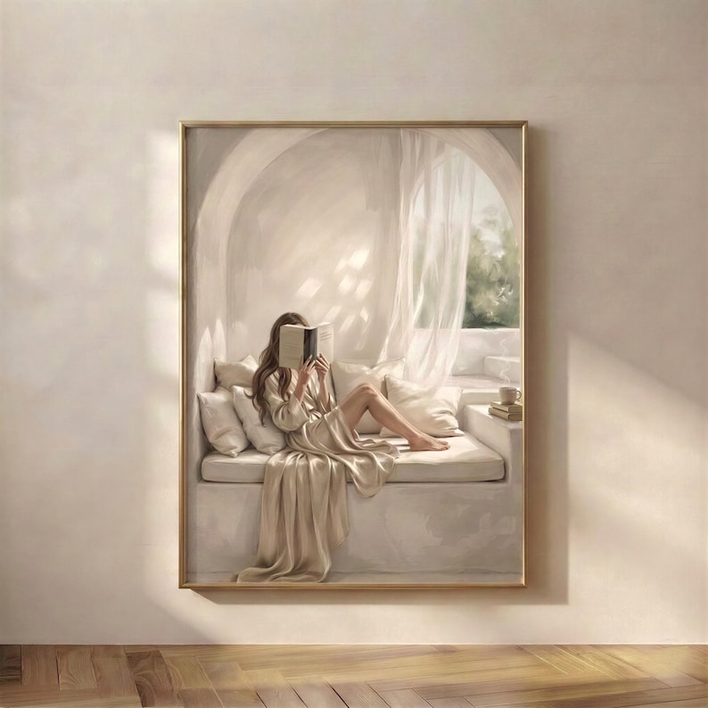 Woman with brunette hair reading in a quiet arched reading nook, neutral wall art print hung in a cozy reading corner with soft plaster walls, draped linen, and warm beige daylight, thin gold frame, no mat.