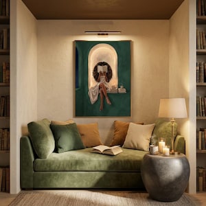 Emerald green reading nook art print hung above a green velvet daybed in a cosy library alcove, lit by a brass picture light, with bookshelves either side and candles on a stone side table.