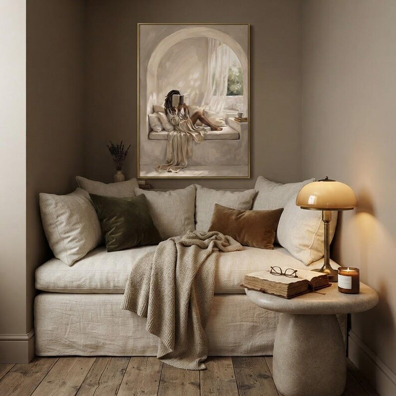 Black woman with locs reading in a quiet arched reading nook, neutral wall art print hung in a cozy reading corner with a cushioned seat, soft plaster arch, draped linen, and warm beige daylight, thin gold frame, no mat.