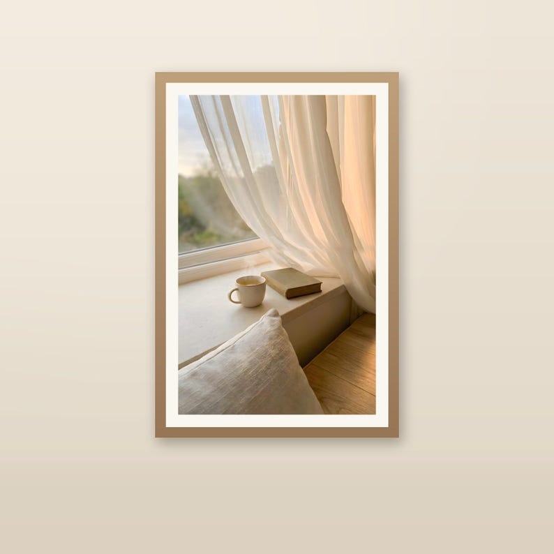 Japandi window seat wall art print with wooden frame, book and coffee on sunlit ledge, sheer beige curtains, minimalist Scandinavian home decor, slow living interior, neutral calming room accent, digital printable art