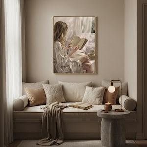Cushioned reading nook with a knitted throw and brass lamp, the woman reading art print framed in gold on the wall above