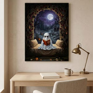 The graveyard arch ghost reading print framed above a pale oak desk with a stoneware mug and a brass lamp