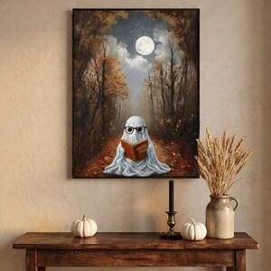 The autumn forest ghost reading print framed above an entryway console styled for autumn with white pumpkins and dried wheat