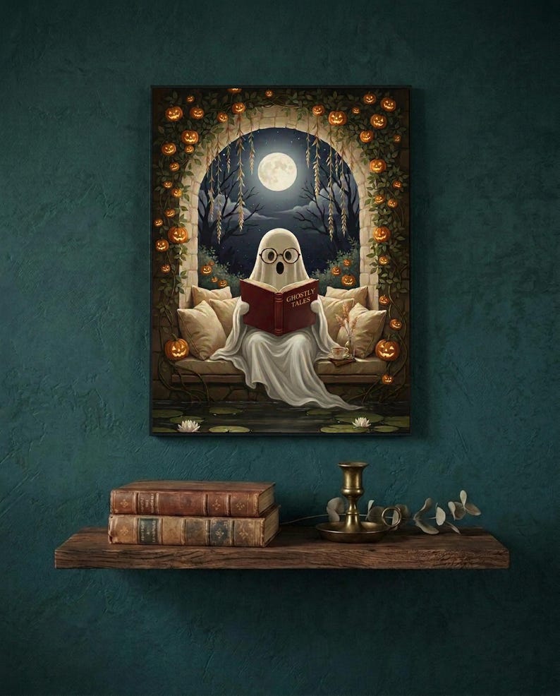The pumpkin arch ghost reading print framed on a deep teal wall above a narrow shelf with antique books and a brass candlestick