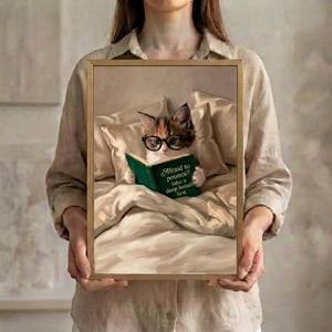 Person in a linen shirt holding the framed calico cat reading print, showing its true scale