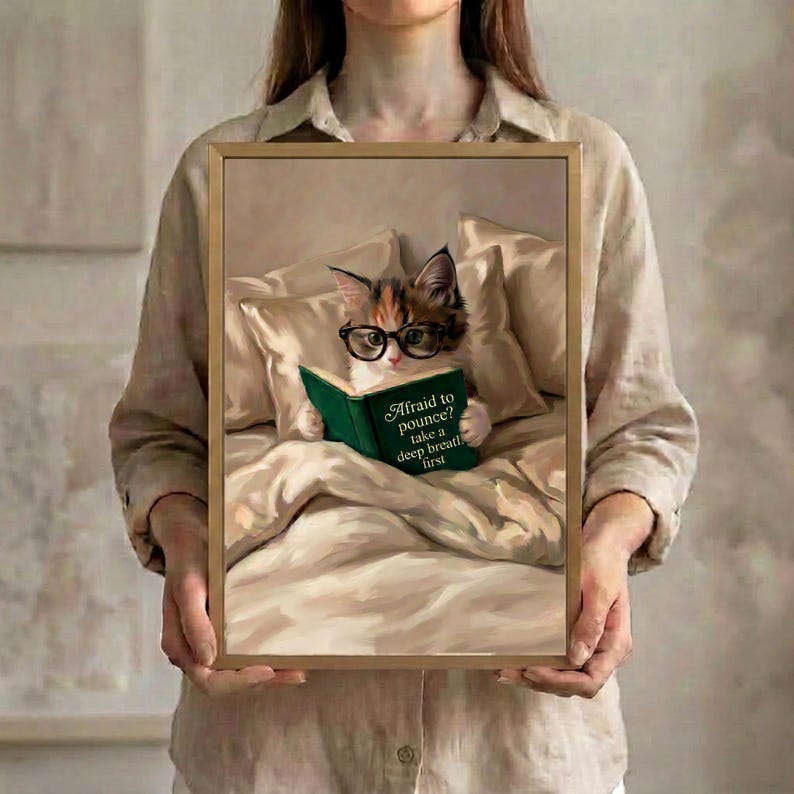 Person in a linen shirt holding the framed calico cat reading print, showing its true scale