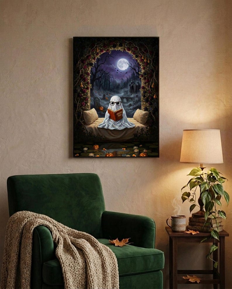 The graveyard arch ghost reading print framed above a green velvet armchair with a knit throw and a warm lamp