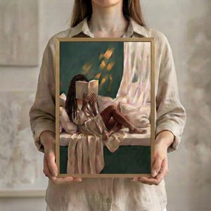 The emerald green art print of a Black woman reading on a window seat in a thin gold frame, held up in both hands to show its size.