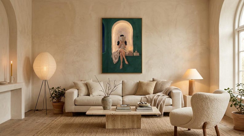 Emerald green reading nook art print above a cream linen sofa in an airy plaster living room, with a boucle armchair, a travertine coffee table, paper lanterns and potted plants.