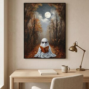 The autumn forest ghost reading print framed above a pale oak desk with a stoneware mug and a brass lamp