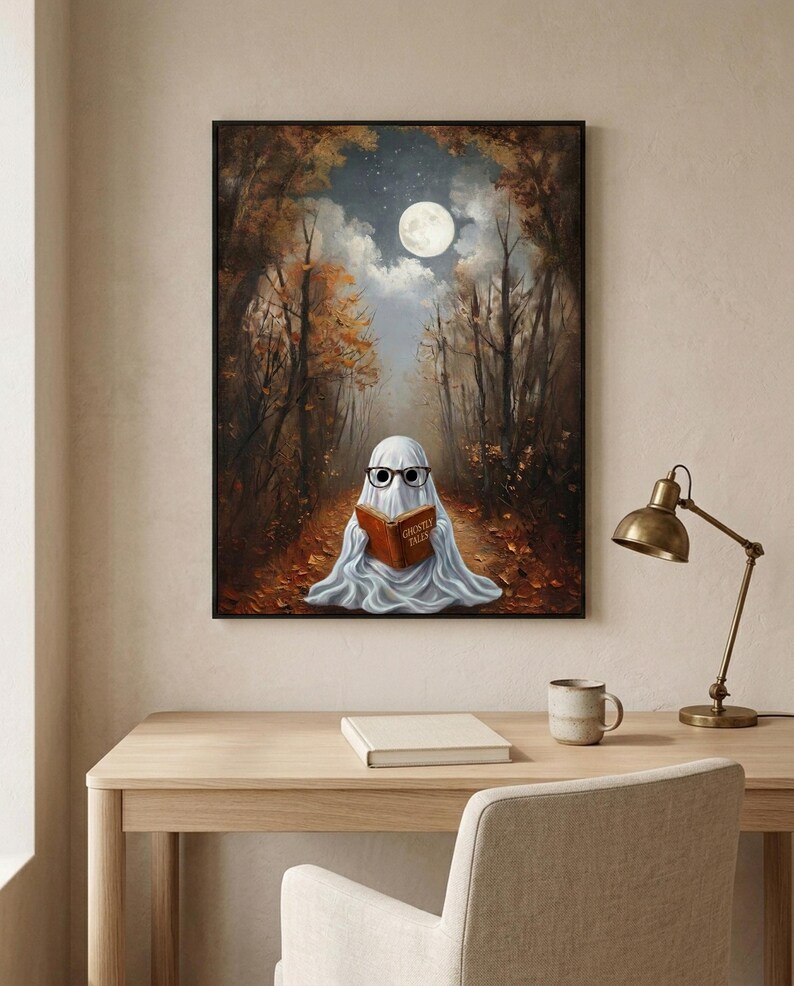 The autumn forest ghost reading print framed above a pale oak desk with a stoneware mug and a brass lamp