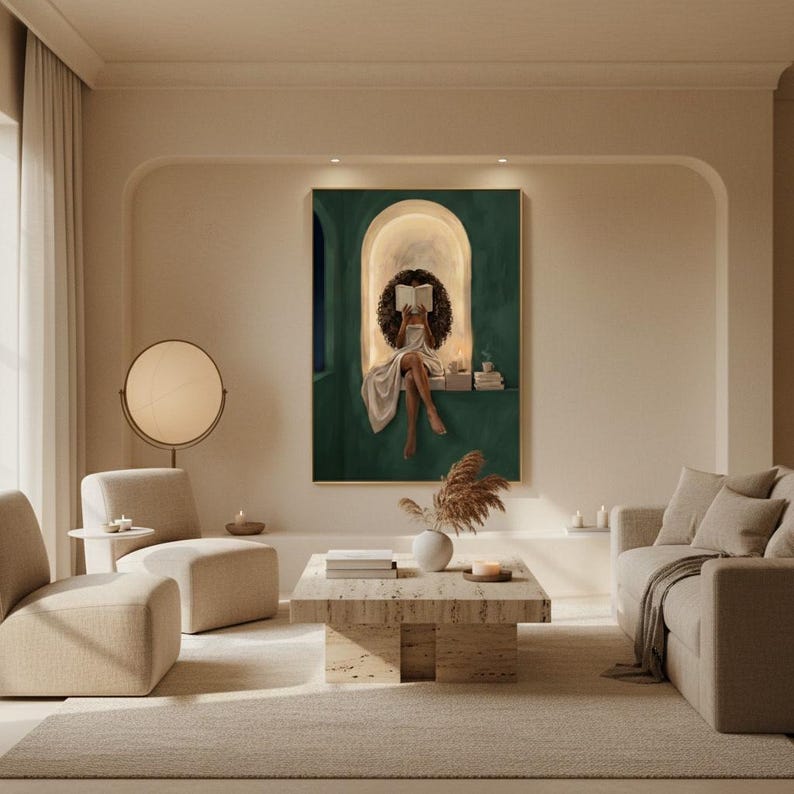 Emerald green reading nook art print in a thin gold frame on the arched wall of a minimalist beige living room with boucle chairs, a travertine coffee table and dried pampas grass.