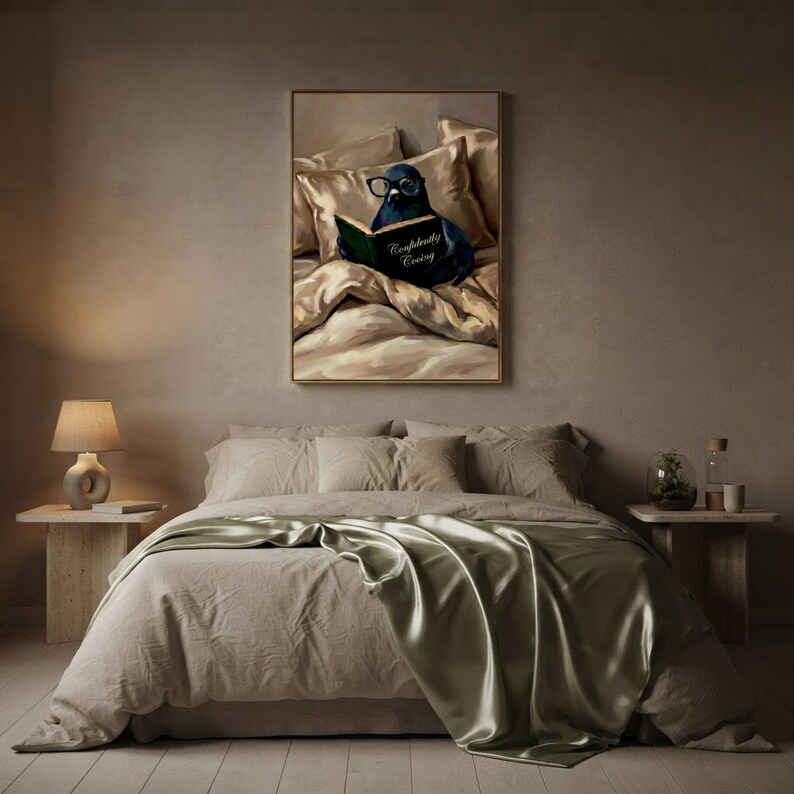The pigeon reading print framed above a bed with soft linen bedding and a sage green throw, beside a small lamp and stone nightstands