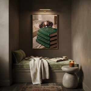 Framed dog peeking over books print in a quiet reading corner beside a low sofa and a small lamp