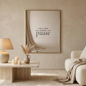 You Are Allowed to Pause styled in a wide calm neutral living room view, hung in a thin gold frame with no mat. neutral printable wall art, minimalist home decor, Japandi style, calm living room decor, slow living digital download.