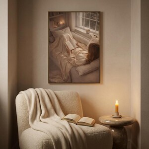 Reading nook wall art framed above a cozy boucle armchair with a knit throw, open book, and lit candle on a side table.