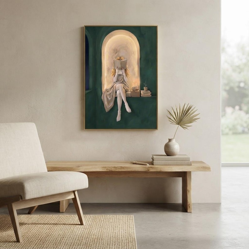 Emerald green reading nook art print on a pale plaster wall above a live-edge oak bench holding a stoneware vase with a dried palm, beside a linen armchair and a garden window.