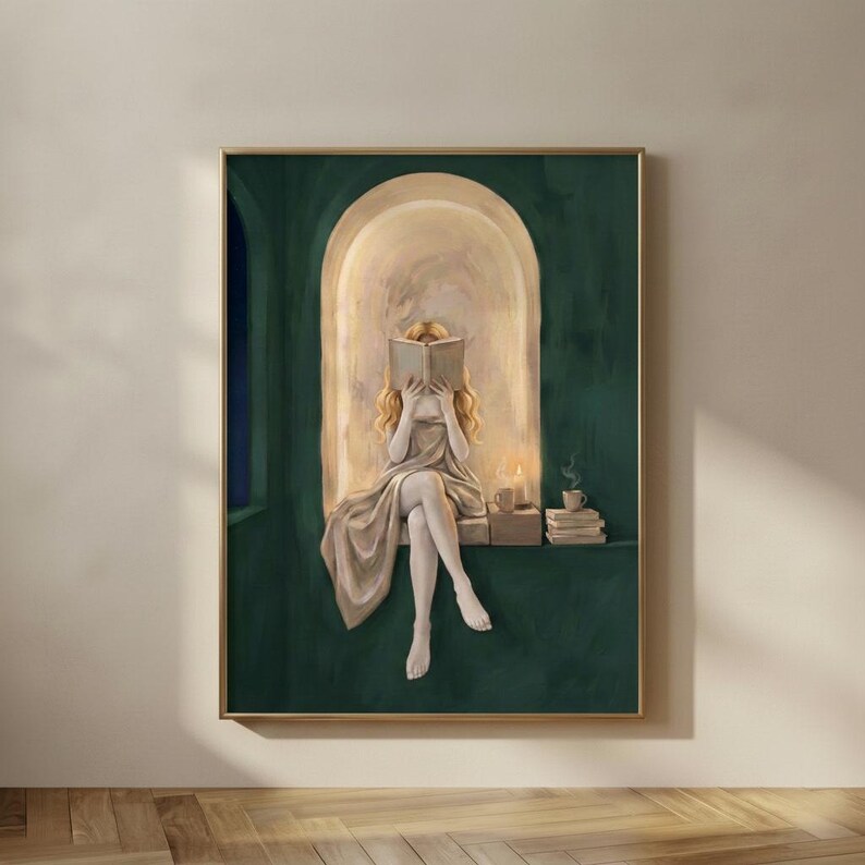 Emerald green reading nook art print of a blonde woman reading by candlelight, in a thin gold frame on a plain plaster wall.