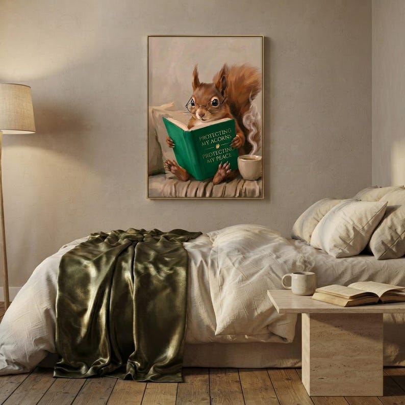 Red squirrel reading art print framed on a textured plaster bedroom wall above linen bedding in soft morning light