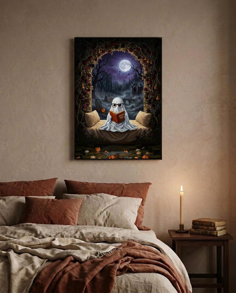 The graveyard arch ghost reading print framed above a bed with linen bedding and a lit candle on the nightstand
