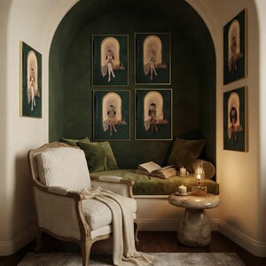 Seven emerald green reading nook art prints around a deep green arched alcove, four inside it and three on the cream wall either side, above an olive velvet daybed with an oil lamp, a lit candle and an open book.