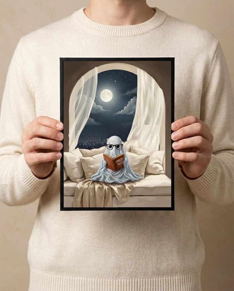 The moonlit bed ghost reading print held in both hands by a person in a cream sweater, showing its scale