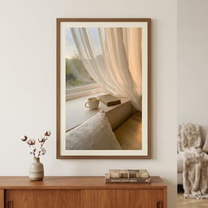 Window seat wall art print mockup with wood frame and cotton plants, book and coffee on sunlit ledge, sheer curtains Japandi decor, minimalist Scandinavian interior, neutral beige home accent, digital printable art