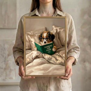 Person in a linen shirt holding the framed dog reading print in a slim gold frame, showing its true scale against a soft neutral background