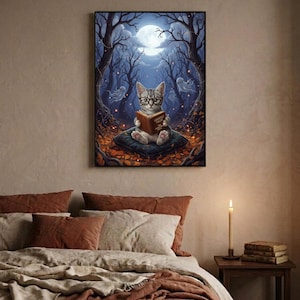 The kitten and ghosts ghost reading print framed above a bed with linen bedding and a lit candle on the nightstand