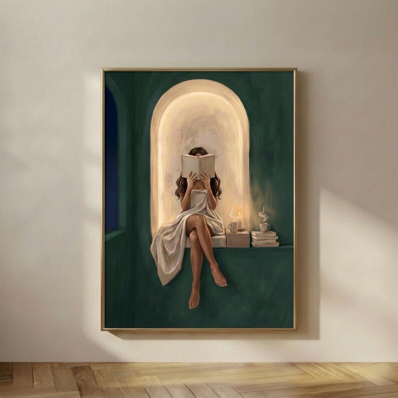 Emerald green reading nook art print of a woman with brown wavy hair reading by candlelight, in a thin gold frame on a plain plaster wall.