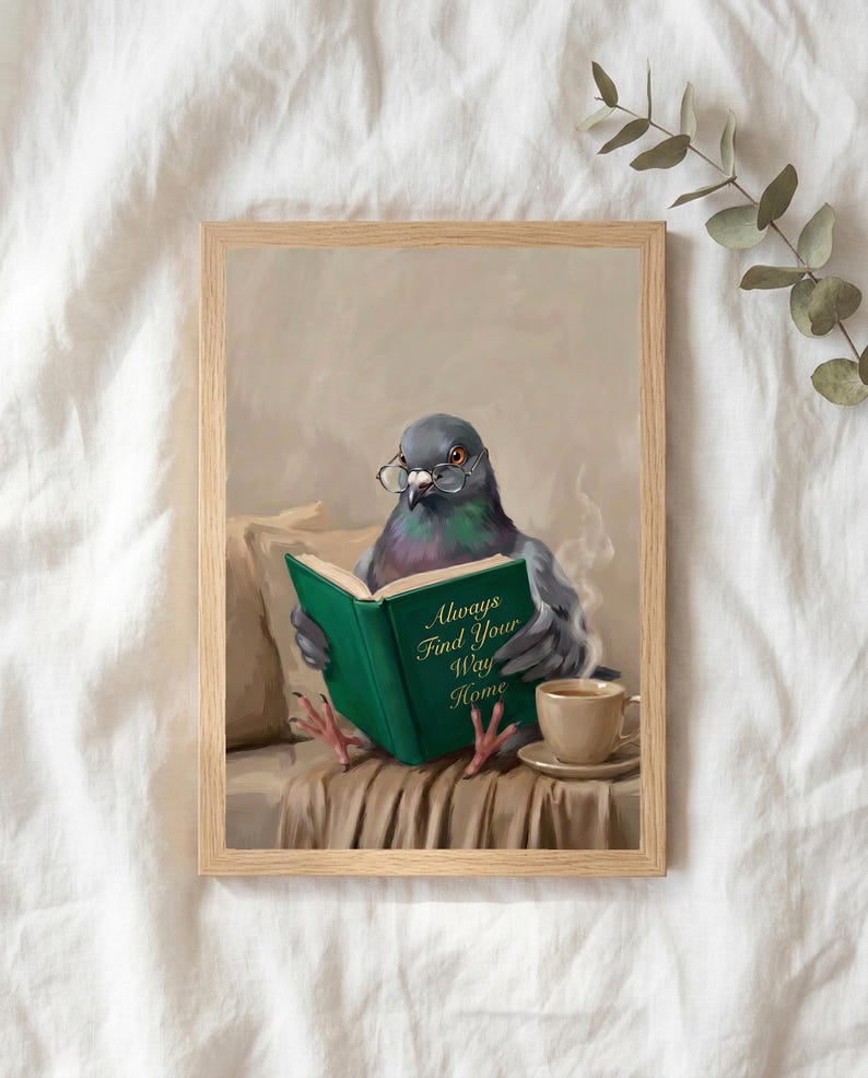 The pigeon reading print in a thin natural oak frame lying on white linen with a sprig of eucalyptus