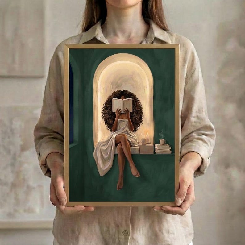 One emerald green reading nook art print from the set of six, in a thin gold frame, held up in both hands to show its size.
