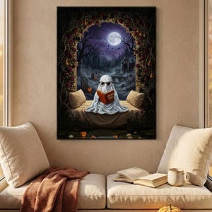 The graveyard arch ghost reading print framed above a cushioned window bench with a wool throw and a small pumpkin