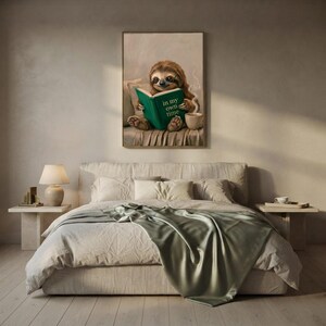 Sloth reading art print framed on a textured plaster bedroom wall above linen bedding in soft morning light