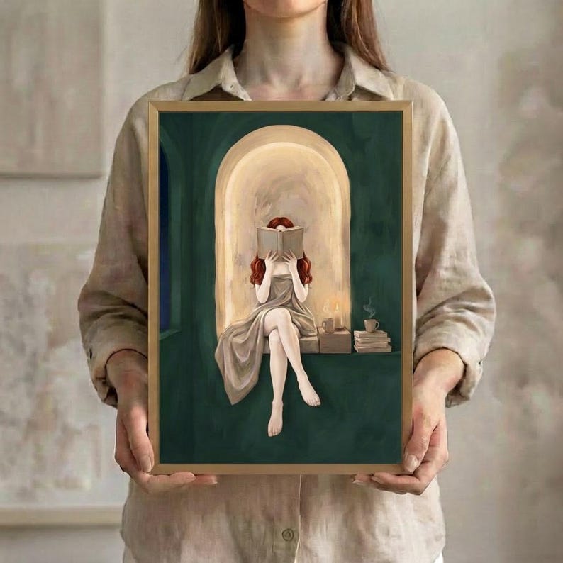 The red-haired woman reading in an emerald green arched nook art print in a thin gold frame, held up in both hands to show its size.
