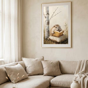 Framed woodland animal print hanging above a cream sectional sofa in a bright neutral living room with linen cushions and a window