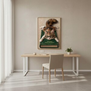 Kitten in glasses wall art framed above a restrained workspace with pale walls and a natural wood desk