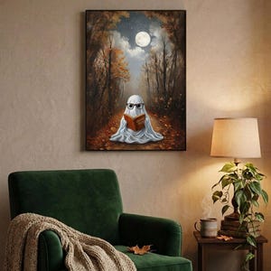The autumn forest ghost reading print framed above a green velvet armchair with a knit throw and a warm lamp