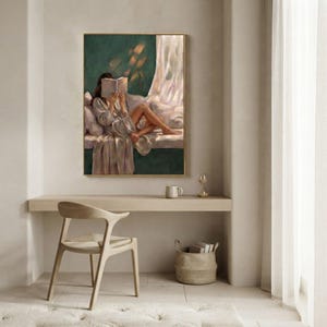 Emerald green wall art framed above a wooden desk in a bright minimalist nook with a woven chair, a mug and hourglass, and a basket of books below.