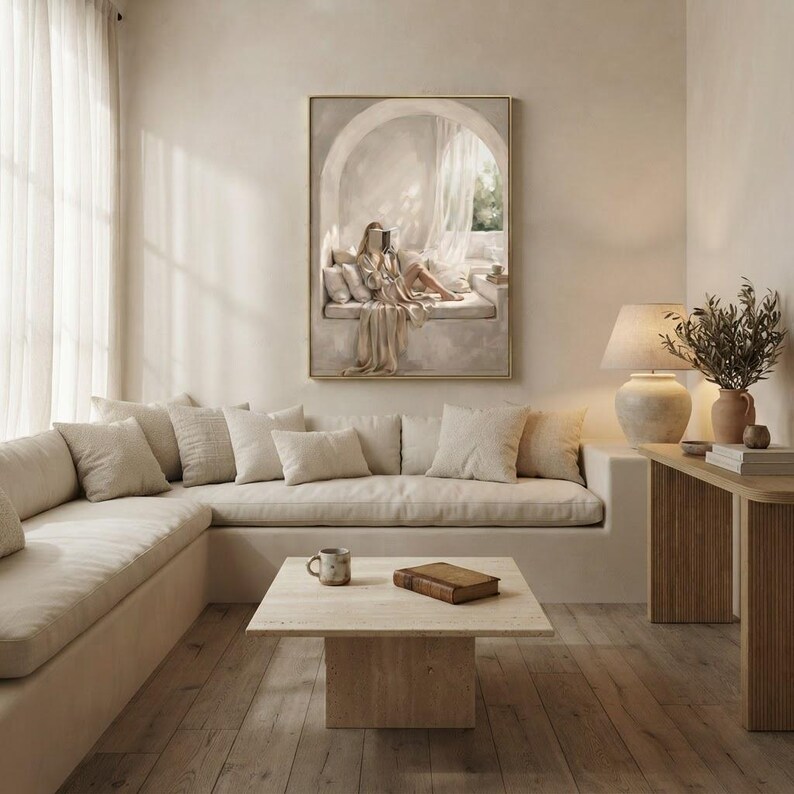 Same woman reading nook art in a calm light-filled living room with warm plaster walls and a thin gold frame, no mat.