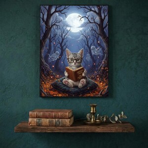 The kitten and ghosts ghost reading print framed on a deep teal wall above a narrow shelf with antique books and a brass candlestick