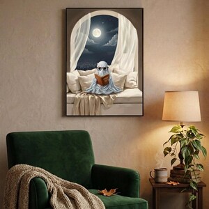 The moonlit bed ghost reading print framed above a green velvet armchair with a knit throw and a warm lamp
