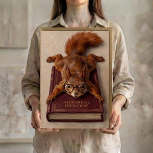 A person in a linen shirt holding the Arboreal Biology squirrel art print in a slim gold frame against a soft neutral background